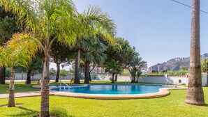 A swimming pool surrounded by palm trees and a grassy area. - "El Cid" Holiday Apartment with Sea View, Pool, Garden & Terrace (Denia)