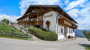 A traditional chalet with a wooden balcony, a stone staircase, and a view of the mountains. - Holiday Apartment 'Schwalbennest' with Mountain View, Wi-Fi, Balcony and Garden (Mühlbach)