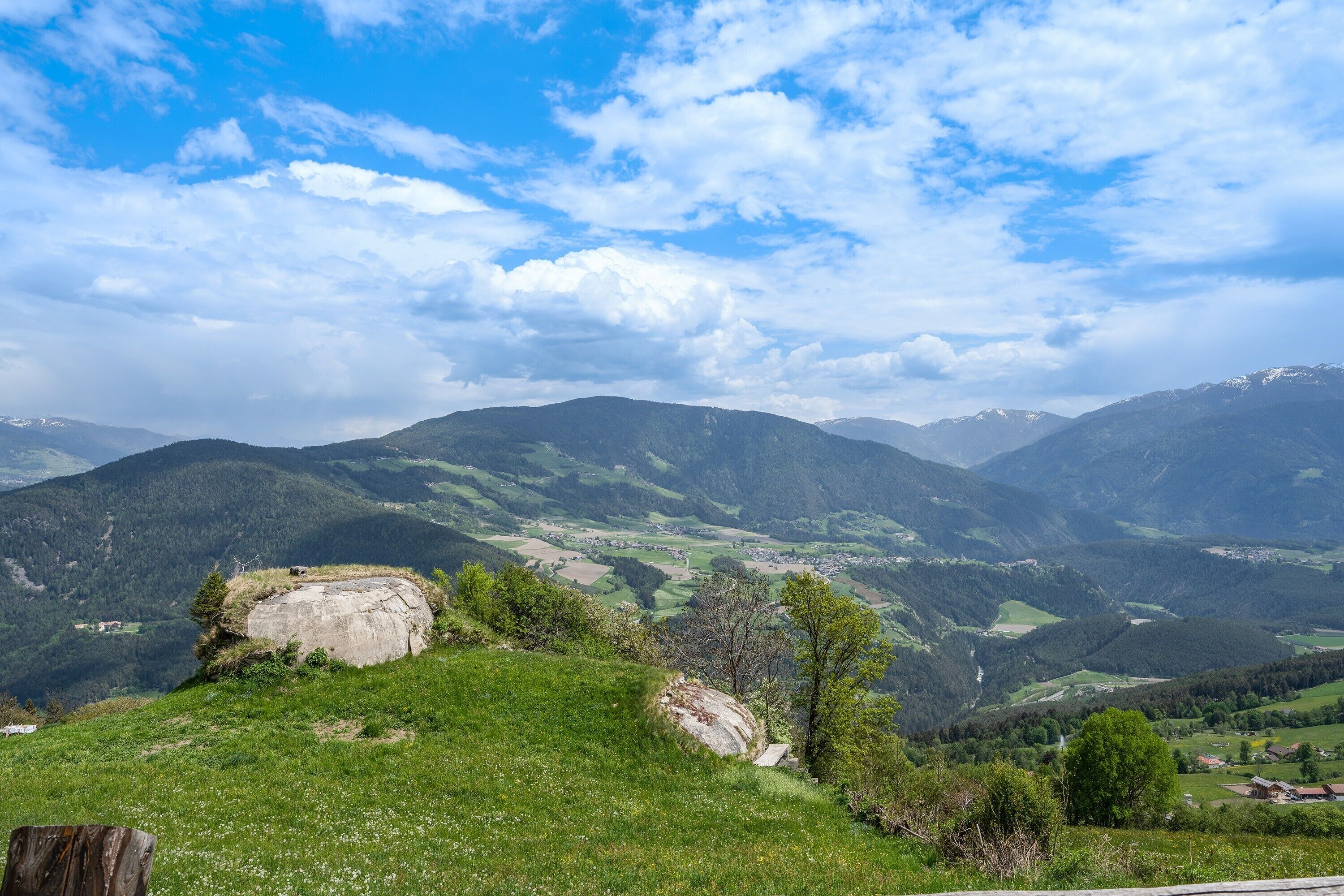 Paesaggio montuoso con cielo sereno, dolci colline e una roccia imponente.