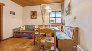 A cozy room with a wooden ceiling, a sofa, a bench, a table, and a window with curtains. - Holiday Apartment 'Schwalbennest' with Mountain View, Wi-Fi, Balcony and Garden (Mühlbach)