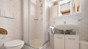 A modern bathroom with a shower, toilet, sink, and cabinet.