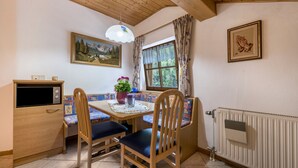 A cozy room with a wooden ceiling, a table with chairs, a radiator, and a painting on the wall. - Holiday Apartment "Waldesruh" with Mountain View, Balcony & Wi-Fi (Mühlbach)