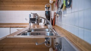 A kitchen with wooden cabinetry, stainless steel sink, and a modern faucet. - Holiday Apartment "Waldesruh" with Mountain View, Balcony & Wi-Fi (Mühlbach)