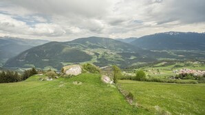 Een bergachtig landschap met een dorp en een opvallende rotsformatie.
