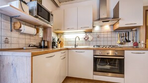 Une cuisine avec des armoires blanches, un four en acier inoxydable, un four à micro-ondes et un plan de travail en bois.