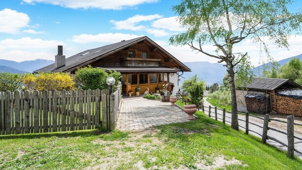 Une maison en bois avec un balcon, une allée pavée et une clôture en bois.
