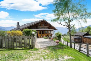 Une maison en bois avec un balcon, une allée pavée et une clôture en bois.