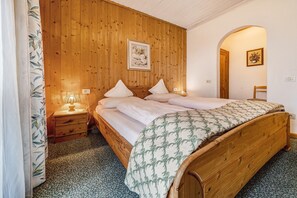 Une chambre à coucher aux murs lambrissés, avec un lit, des tables de chevet et une petite table de nuit.