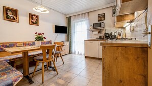 Une cuisine avec un banc en bois, un téléviseur et un four à micro-ondes.