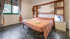 A bedroom with a bed, bedside table, lamp, and a window with curtains. - Holiday Home Villetta Luisa with Mountain View & Terraces (Villa San Pietro)