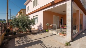 A two-story building with a covered patio area, potted plants, and a metal railing. - Holiday Home Villetta Luisa with Mountain View & Terraces (Villa San Pietro)
