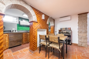 Uma cozinha com piso de madeira em padrão herringbone, uma mesa de jantar com cadeiras e um pilar de pedra.