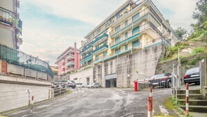 A multi-story building with balconies, a parking area with cars, and a staircase leading up to the building. - GuestHost - Our cozy apartment is located in a strategic position to visit the well-known Ligurian Riviera, not only the lively Rapallo with its shops, but also San Michele di Pagana, Santa Margherita Ligure and Portofino. The flat can accommodate up to  (Rapallo)