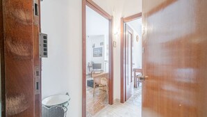 A hallway with a wooden door, a trash bin, and a wicker chair. - GuestHost - Our cozy apartment is located in a strategic position to visit the well-known Ligurian Riviera, not only the lively Rapallo with its shops, but also San Michele di Pagana, Santa Margherita Ligure and Portofino. The flat can accommodate up to  (Rapallo)