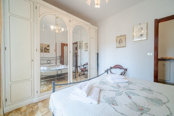 A bedroom with a bed, a wardrobe, a mirror, and a chandelier. - GuestHost - Our cozy apartment is located in a strategic position to visit the well-known Ligurian Riviera, not only the lively Rapallo with its shops, but also San Michele di Pagana, Santa Margherita Ligure and Portofino. The flat can accommodate up to  (Rapallo)