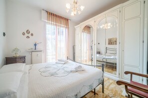 A bedroom with a bed, a nightstand, a dresser, a mirror, and a bench.
