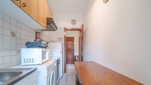 A narrow kitchen with a washing machine, microwave, and a wooden table. - GuestHost - Our cozy apartment is located in a strategic position to visit the well-known Ligurian Riviera, not only the lively Rapallo with its shops, but also San Michele di Pagana, Santa Margherita Ligure and Portofino. The flat can accommodate up to  (Rapallo)