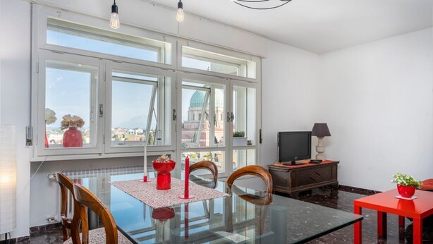 En matplats med ett glasbord, tr ästolar, en röd vas och en tv som står på ett träskåp.