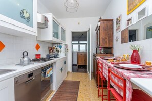 A compact kitchen with a dishwasher, a stove, and a dining area with a table set for two.