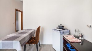 Uma pequena cozinha compacta com mesa, cadeira, geladeira e cafeteira.