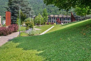 A grassy area with a pathway leading to a modern building with a unique roof structure.