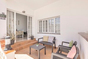 A patio with a table, chairs, and a bench. There is a window with blinds, a door leading to an indoor area, and a sign with a QR code. - Vacation Home Casa Eri close to the Beach with Pool, Terrace & Wi-Fi (Corralejo)