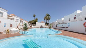 En swimmingpool med liggestole, palmer og en redningskrans ved kanten.