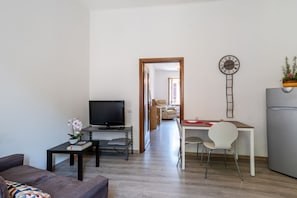 Een moderne woonkamer met een televisie, bank en een eetgedeelte met een tafel en stoelen.