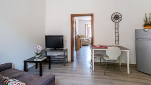 A modern living room with a TV, sofa, and a dining area with a table and chairs. - GuestHost - Cozy, completely renovated 47sqm apartment located on the 3rd floor of a building WITHOUT elevator. The apartment is accessed via an external balcony overlooking the quiet internal courtyard.The accommodation is located in an excellent locati (Como)