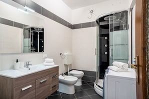 A modern bathroom with a shower, toilet, and vanity.