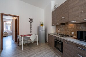 A modern kitchen with a dining area, a refrigerator, a stove, and a clock on the wall.