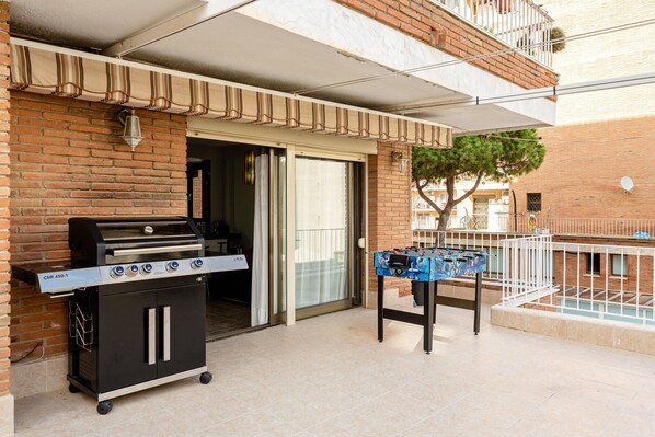 A patio with a grill, a table with a board game, and a brick wall.