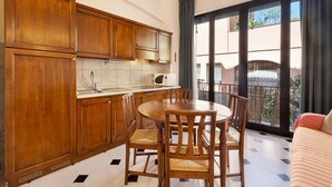Une cuisine avec des meubles en bois, une table à manger avec des chaises, une fenêtre donnant sur l’extérieur et un balcon avec une balustrade.