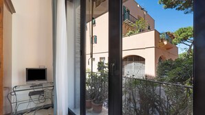 Un balcon avec un téléviseur, un bureau en verre et des plantes en pot.