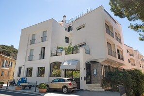 Un immeuble à plusieurs étages doté de balcons, d’une entrée couverte et d’une voiture garée.