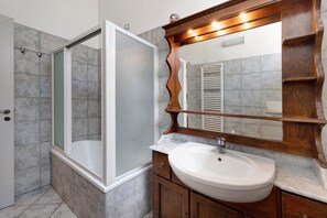 Une salle de bain avec une douche, un lavabo et un miroir.