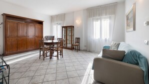 A living room with a sofa, a dining table with chairs, a cabinet, and a glass display cabinet.