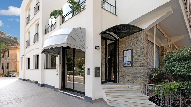 A building with a covered entrance, a stone facade, and a staircase leading to the entrance.