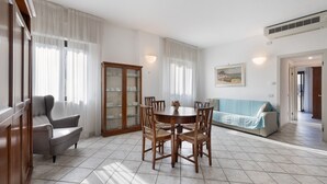 A dining area with a round table, chairs, a sofa, and a cabinet.