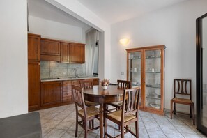 Une cuisine avec des meubles de rangement en bois, une table à manger avec des chaises et un meuble vitré.