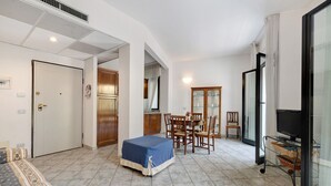 Ein Hotelzimmer mit einem Bett, einem Esstisch mit Stühlen, einem Fernseher und einer Glastür.