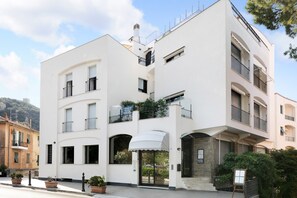 Un edificio de varios pisos con balcones, una entrada cubierta y un letrero.