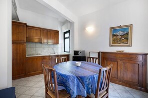 A kitchen with wooden cabinets, a dining table with chairs, and a painting on the wall.
