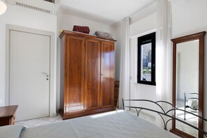 A bedroom with a bed, a wardrobe, a window, and a mirror.