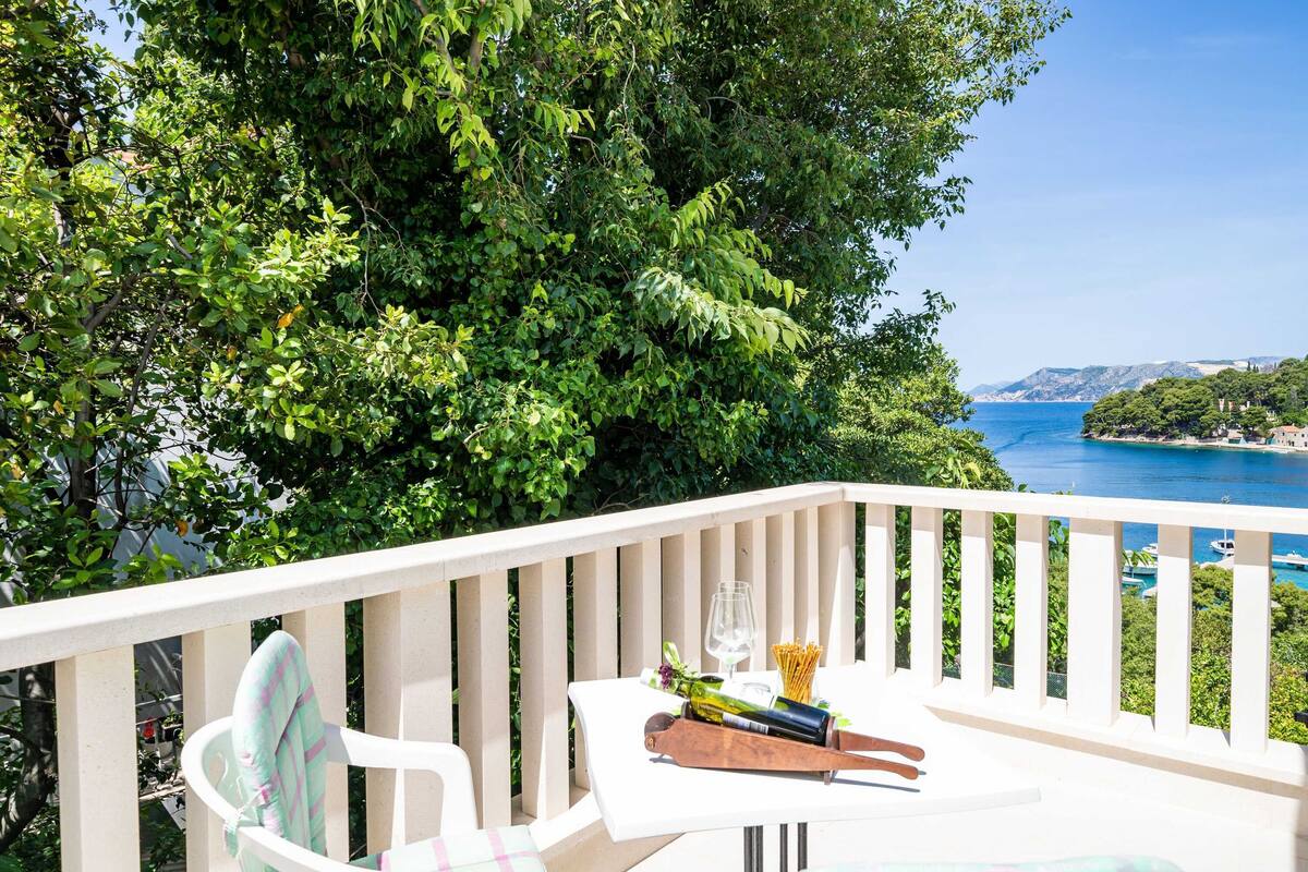 A balcony with a table, a chair, and a bottle of wine.
