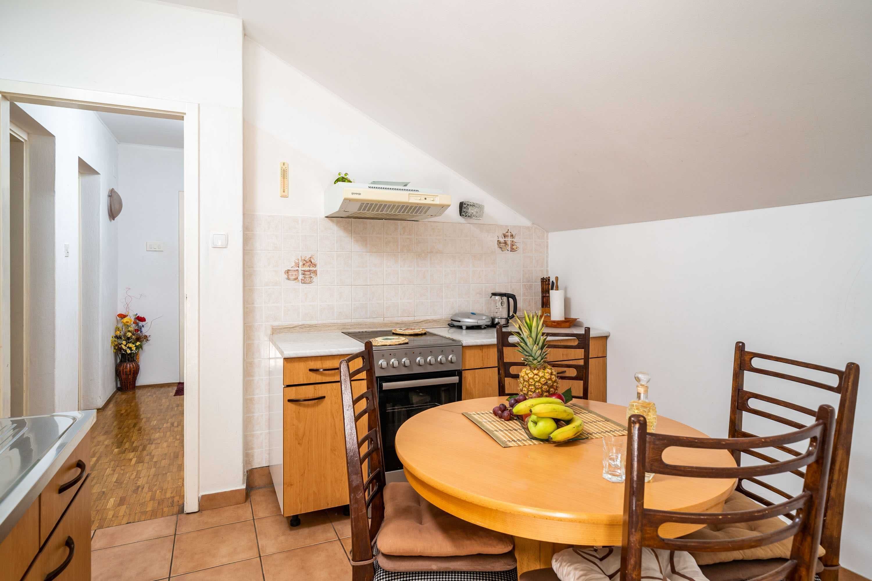 A compact kitchen with wooden cabinets, a stove, and a dining table set for two.