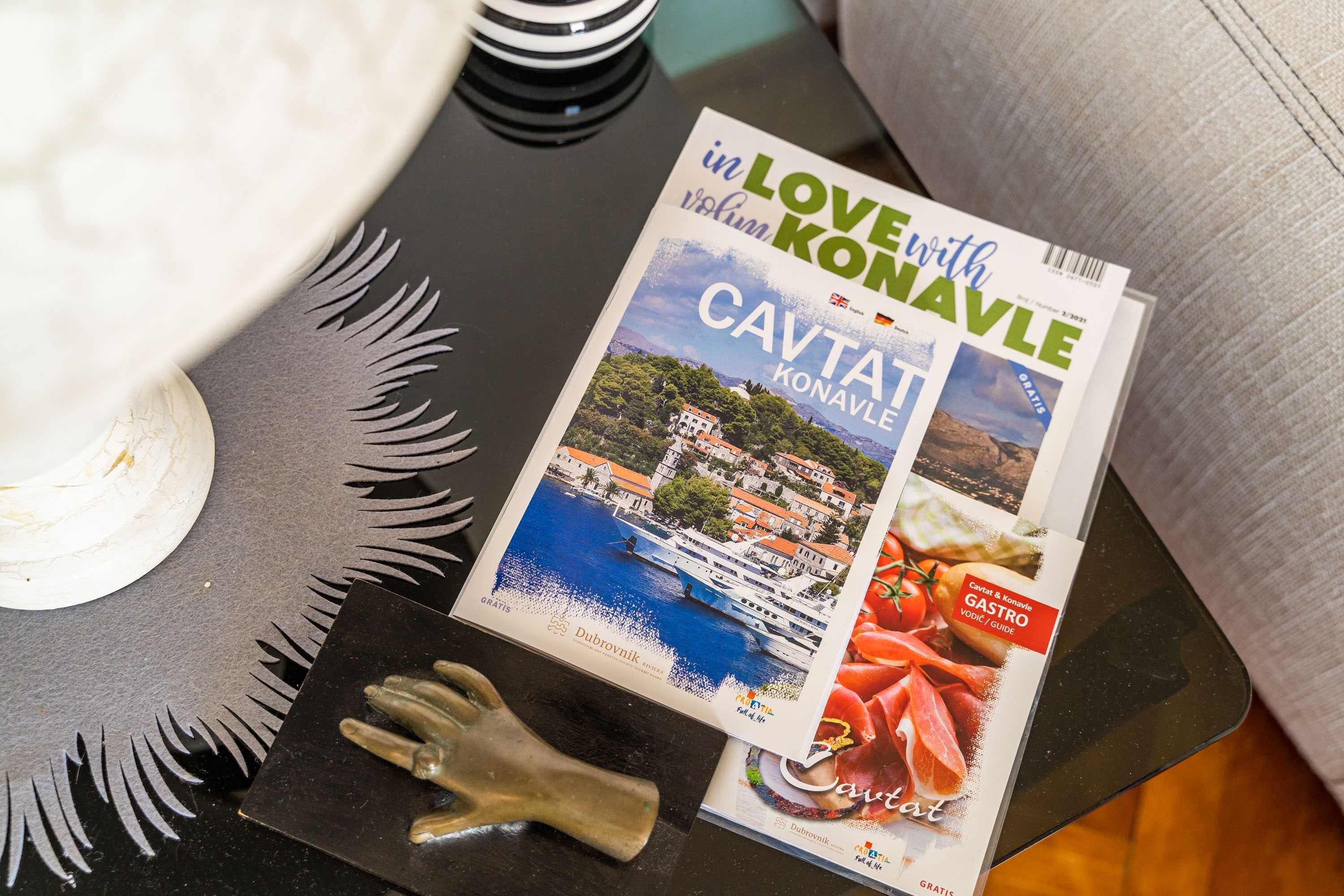 A magazine titled "in LOVE with KONAVLE" on a black table with a decorative item and a white object nearby.