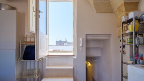 A kitchen with a view to the sea, a metal rack, and a shelf with kitchen items. - Holiday Home 'Dimora Storica Maruggio' with Terrace & A/C (maruggio)
