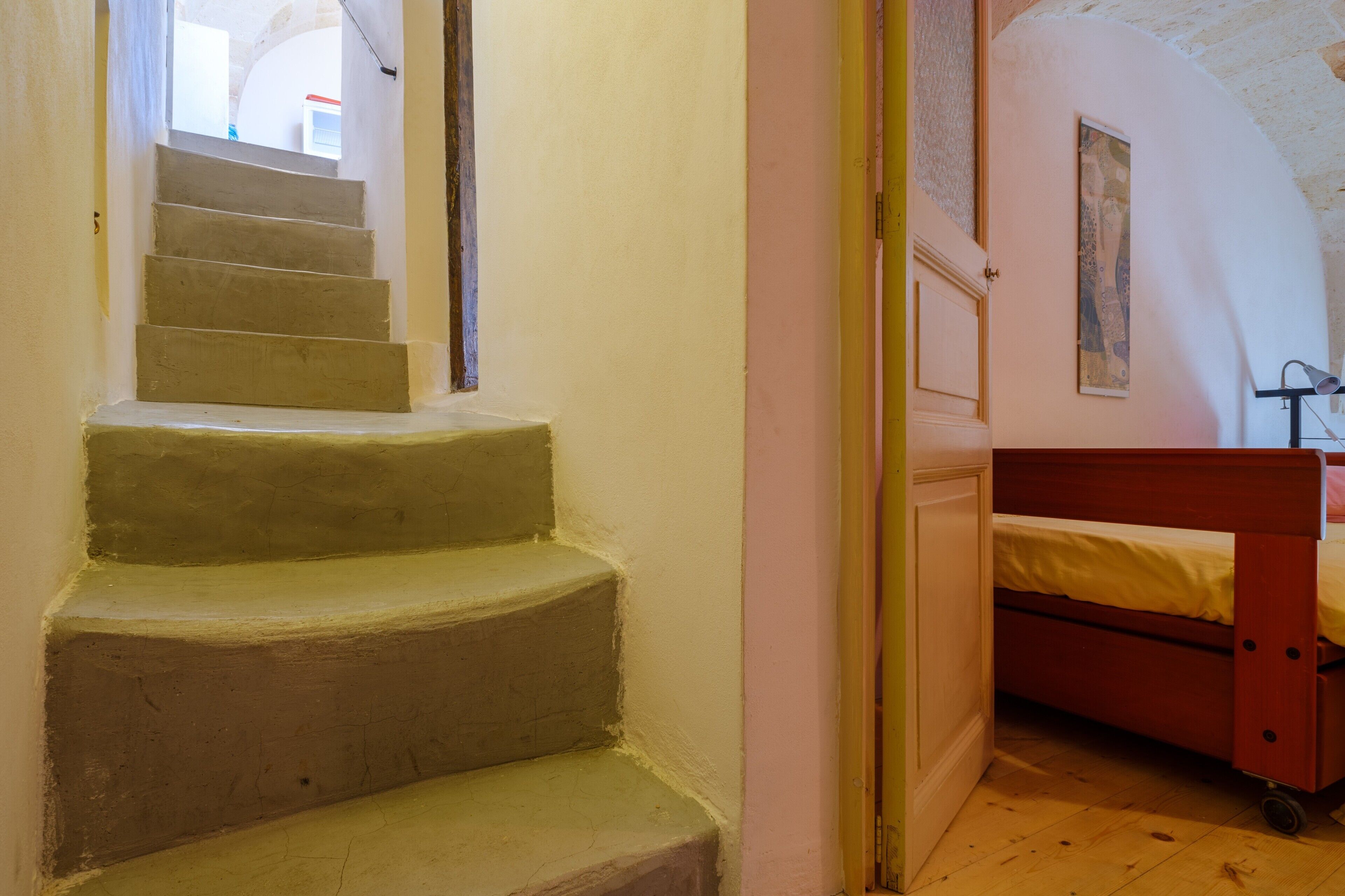 Un escalier menant à une chambre à coucher équipée d’un lit et d’une table de chevet.