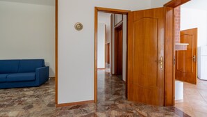 A hallway with a wooden door, a blue sofa, and a tiled floor. - Apartment Casa LILLI 11 posti Near the Sea with Sea View, A/C & Balcony (santa maria al bagno)